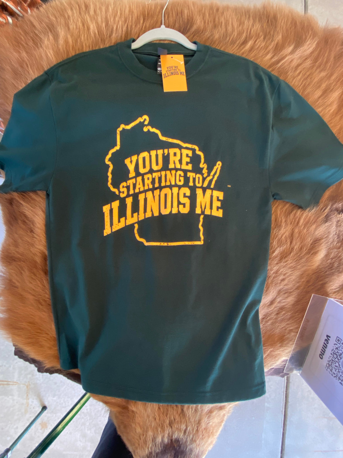Dark green You're Starting to Illinois Me T-shirt with yellow lettering inside a Wisconsin outline.